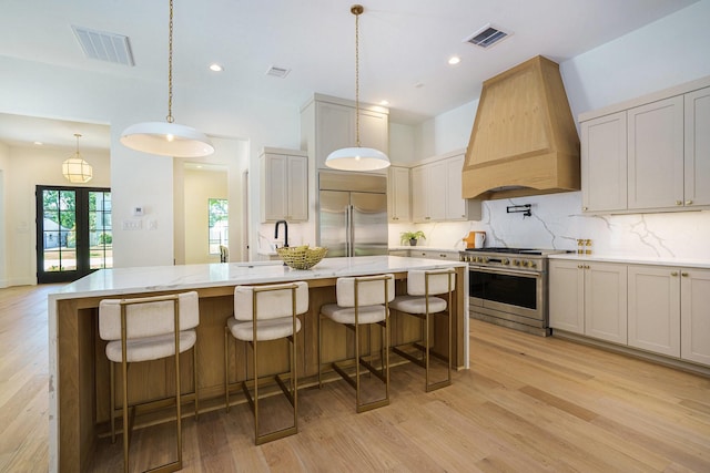 kitchen featuring custom range hood, light wood-style flooring, visible vents, and premium appliances