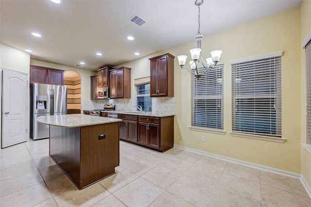 8719 Seguin Cove Ln, Richmond, TX 77407 - kitchen featuring visible vents, appliances with stainless steel finishes, a chandelier, decorative backsplash, and light stone counters