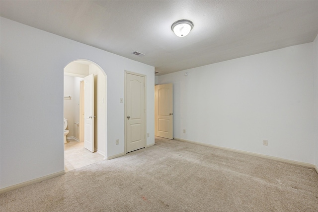 8719 Seguin Cove Ln, Richmond, TX 77407 - unfurnished room featuring light carpet, baseboards, visible vents, and arched walkways