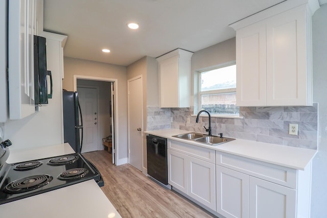 kitchen with a sink, light countertops, white cabinetry, tasteful backsplash, and black appliances