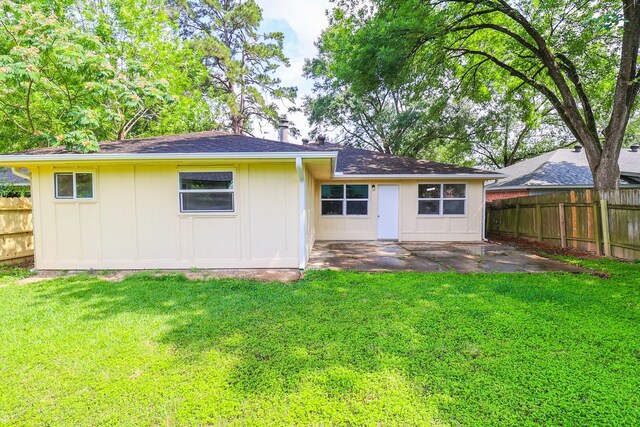 rear view of house with a yard, fence, board and batten siding, and a patio area