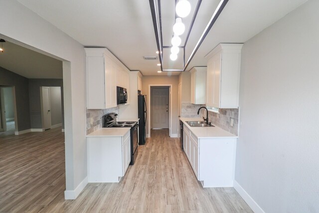 kitchen with a sink, light countertops, decorative backsplash, visible vents, and black appliances