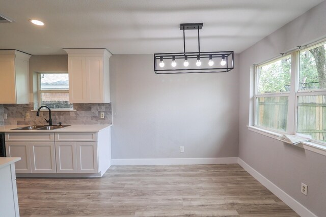 kitchen featuring tasteful backsplash, a sink, light countertops, white cabinets, and recessed lighting