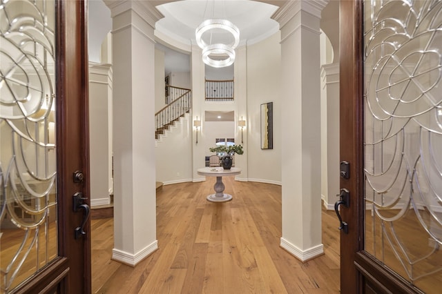 foyer entrance featuring light wood-style flooring, ornate columns, baseboards, and stairs