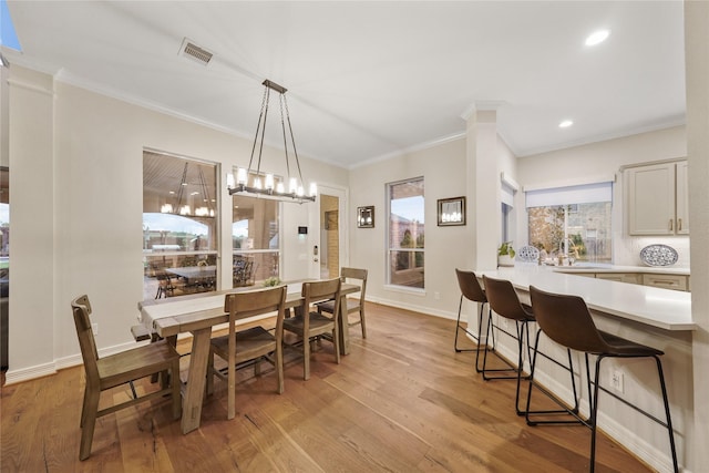 dining area with light wood-style flooring, crown molding, baseboards, and visible vents