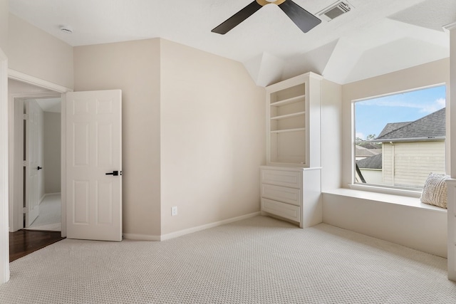 unfurnished bedroom featuring baseboards, vaulted ceiling, carpet flooring, a ceiling fan, and visible vents