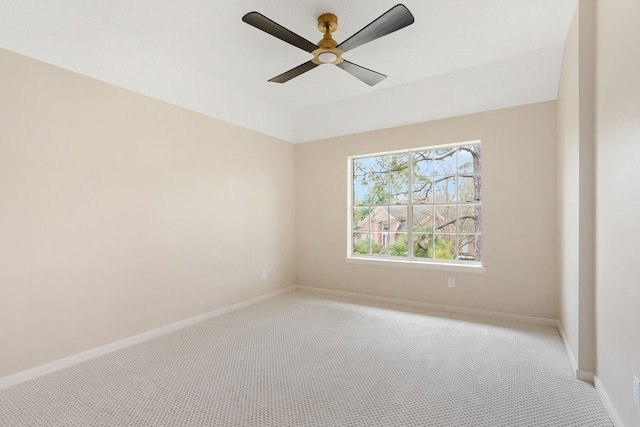 spare room featuring light colored carpet, baseboards, and a ceiling fan
