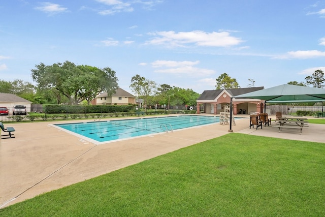 community pool with a patio, fence, and a lawn