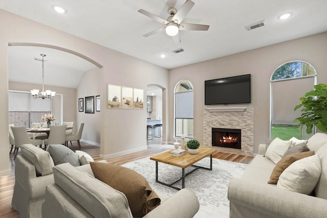 living room featuring arched walkways, baseboards, wood finished floors, and visible vents