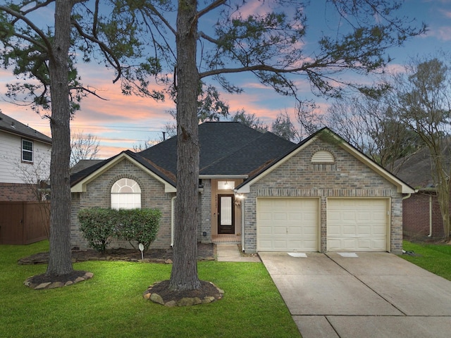 view of front of property featuring roof with shingles, an attached garage, brick siding, concrete driveway, and a yard