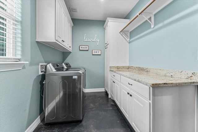 clothes washing area featuring baseboards, cabinet space, and washing machine and clothes dryer
