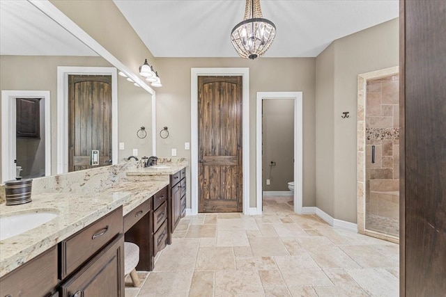 full bath featuring double vanity, a stall shower, baseboards, toilet, and an inviting chandelier