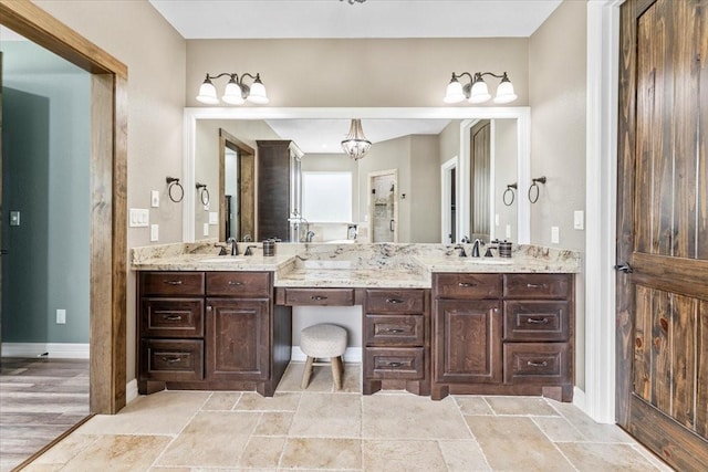 bathroom featuring double vanity, baseboards, stone finish floor, and a sink