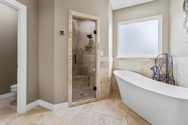 full bathroom featuring tile walls, a soaking tub, a shower stall, and toilet