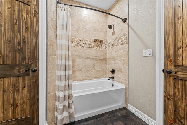 bathroom with baseboards, a textured wall, and shower / bath combo