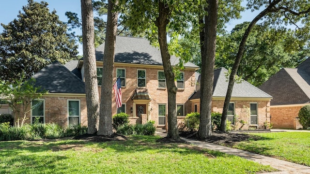 colonial-style house with brick siding, a front lawn, and roof with shingles