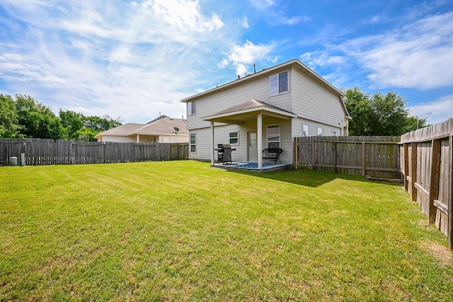 rear view of house with a fenced backyard and a yard