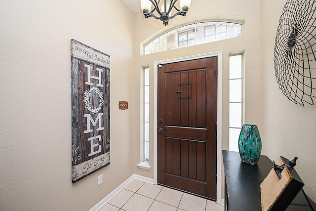 foyer with baseboards, an inviting chandelier, and light tile patterned floors