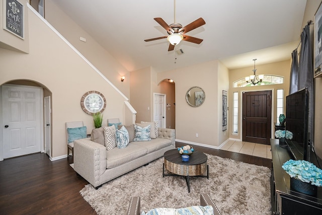 living room featuring wood finished floors, ceiling fan with notable chandelier, arched walkways, baseboards, and visible vents