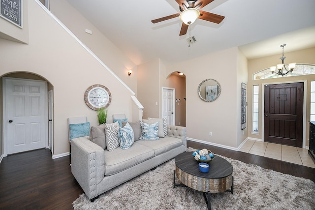 living area with baseboards, arched walkways, wood finished floors, and ceiling fan with notable chandelier