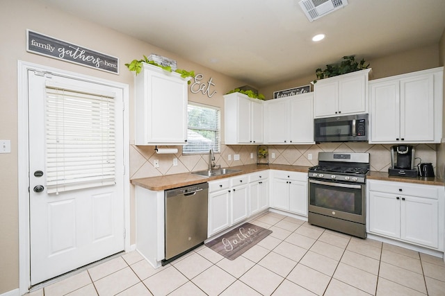 kitchen with a sink, visible vents, white cabinetry, decorative backsplash, and appliances with stainless steel finishes