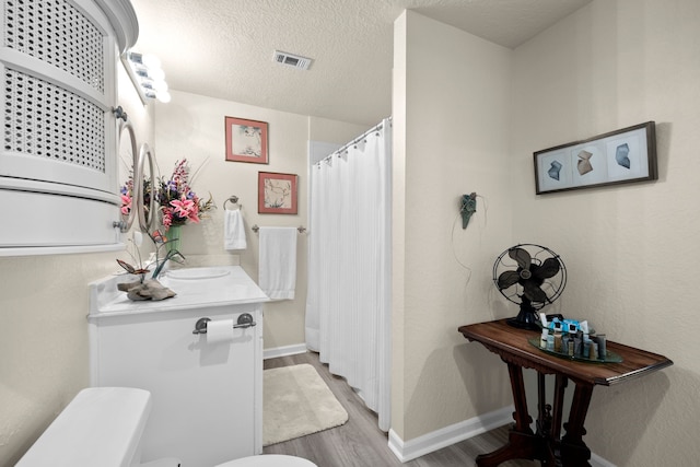 8703 County Road 48, Rosharon, TX 77583 - full bathroom with toilet, wood finished floors, baseboards, vanity, and a textured ceiling