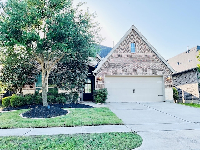 view of front facade with brick siding, an attached garage, driveway, and a front yard