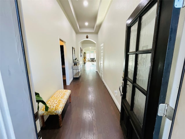 hall with arched walkways, baseboards, and dark wood-style floors