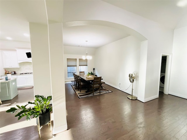 dining space featuring baseboards, arched walkways, dark wood finished floors, and a notable chandelier