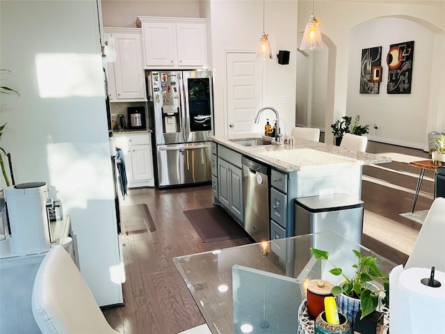 kitchen featuring dark wood-style flooring, decorative light fixtures, appliances with stainless steel finishes, a sink, and white cabinetry