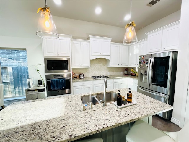 kitchen featuring white cabinets, appliances with stainless steel finishes, a breakfast bar, and a sink