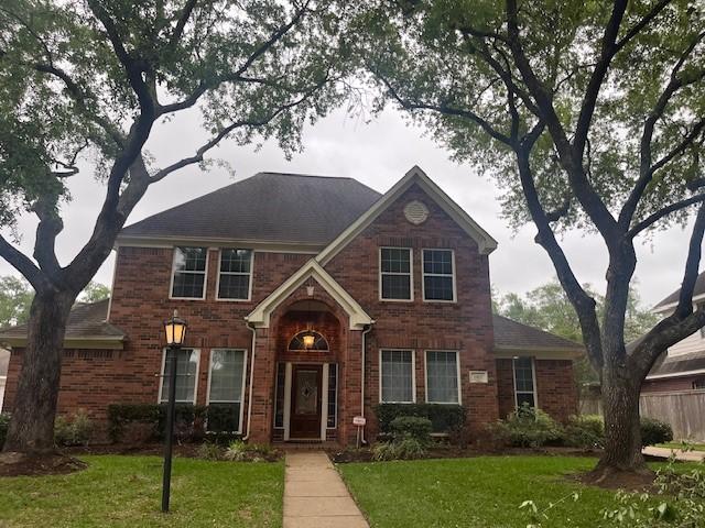 view of front of property featuring fence, brick siding, and a front yard