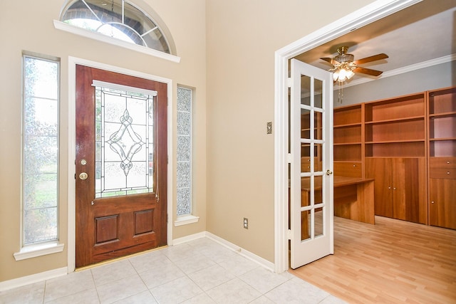 foyer entrance featuring a wealth of natural light, a ceiling fan, baseboards, and ornamental molding