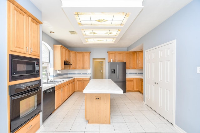 kitchen featuring light brown cabinetry, visible vents, light countertops, a kitchen island, and black appliances
