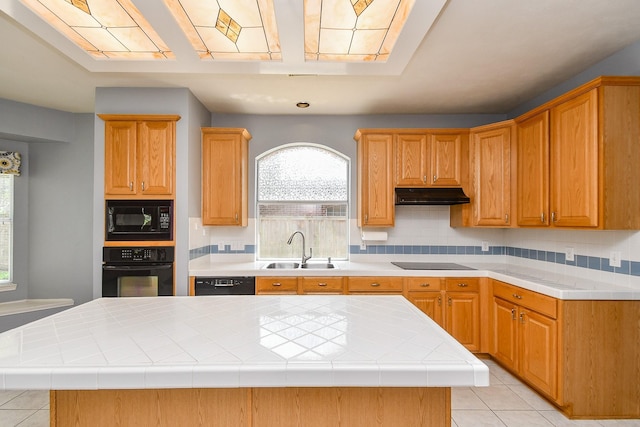 kitchen with tasteful backsplash, a sink, black appliances, light tile patterned floors, and under cabinet range hood
