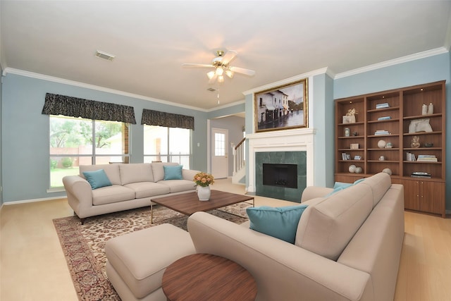 living area featuring baseboards, visible vents, ceiling fan, and crown molding