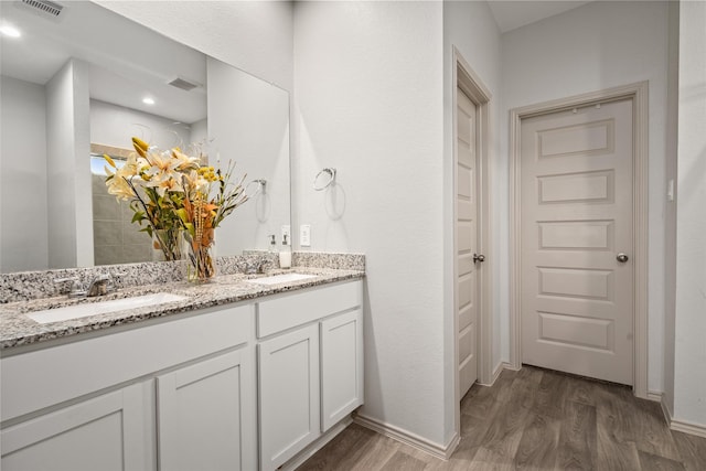 full bathroom featuring a sink, visible vents, double vanity, and wood finished floors