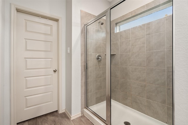 full bath featuring a stall shower, wood finished floors, and baseboards