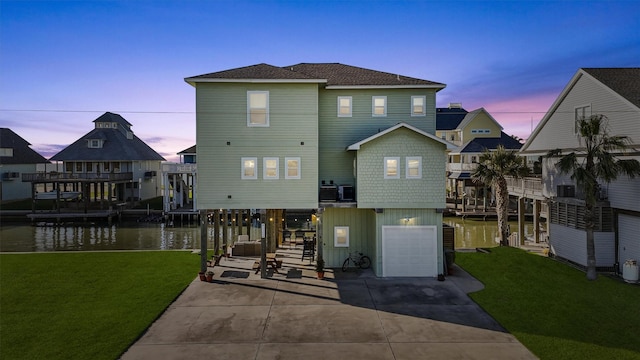 23006 Martes St, Galveston, TX 77554 - rear view of house featuring a garage, concrete driveway, a yard, and a water view