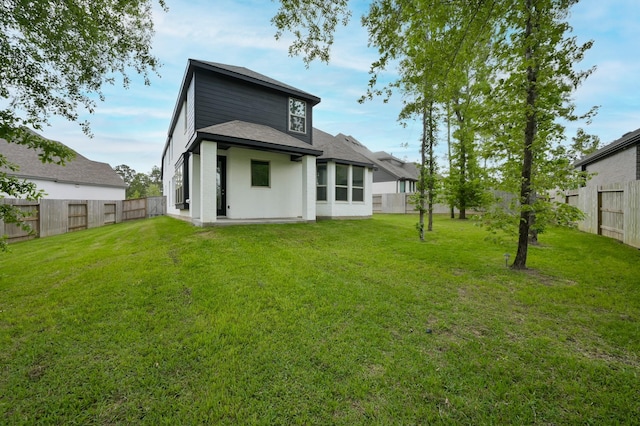 rear view of house with a fenced backyard and a lawn