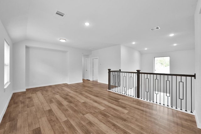 empty room featuring wood finished floors, visible vents, and baseboards