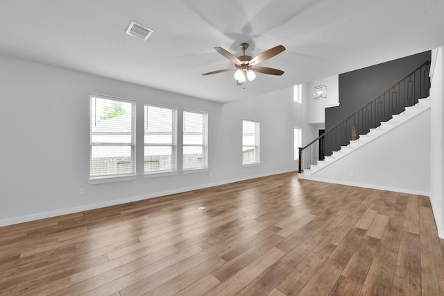 unfurnished living room with baseboards, wood finished floors, a ceiling fan, and stairs