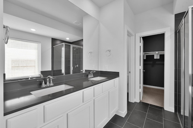 bathroom with double vanity, a shower stall, a spacious closet, and a sink