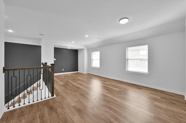 empty room with wood finished floors, baseboards, and recessed lighting