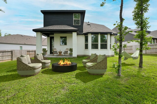 rear view of property with a fire pit, a yard, and a fenced backyard
