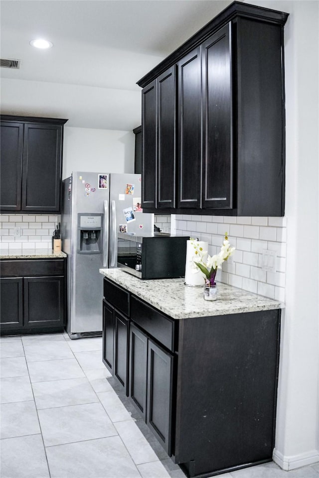 kitchen featuring backsplash, dark cabinetry, and stainless steel appliances