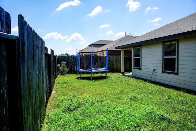 view of yard featuring a trampoline and a fenced backyard