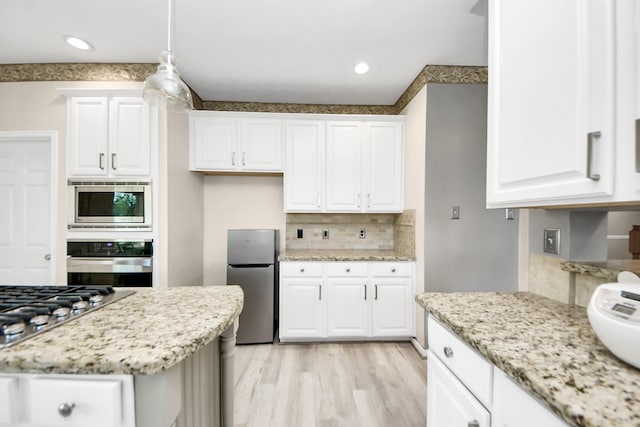4902 Bellmead Dr, Missouri City, TX 77459 - kitchen with appliances with stainless steel finishes, tasteful backsplash, light stone counters, light wood-style floors, and white cabinets
