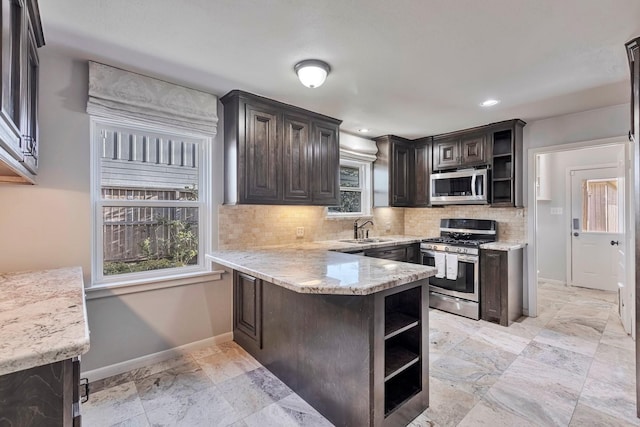 kitchen with baseboards, stainless steel appliances, open shelves, and a sink