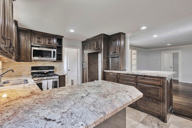 kitchen with a sink, a peninsula, light stone countertops, and stainless steel appliances